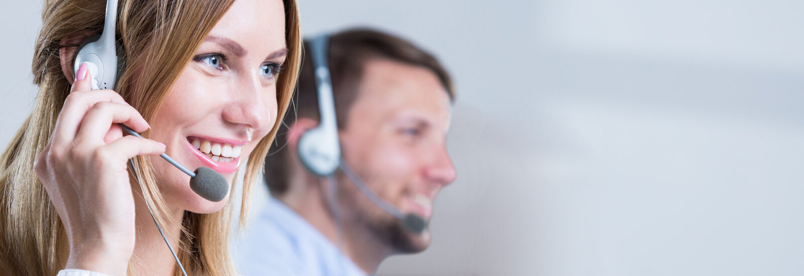 Lächelnde Frau mit Headset telefoniert mit Kunden